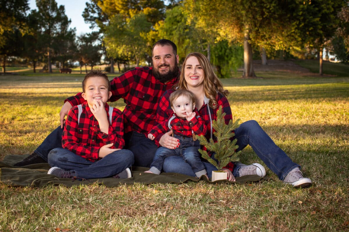 Family in plaid sitting in grass at park